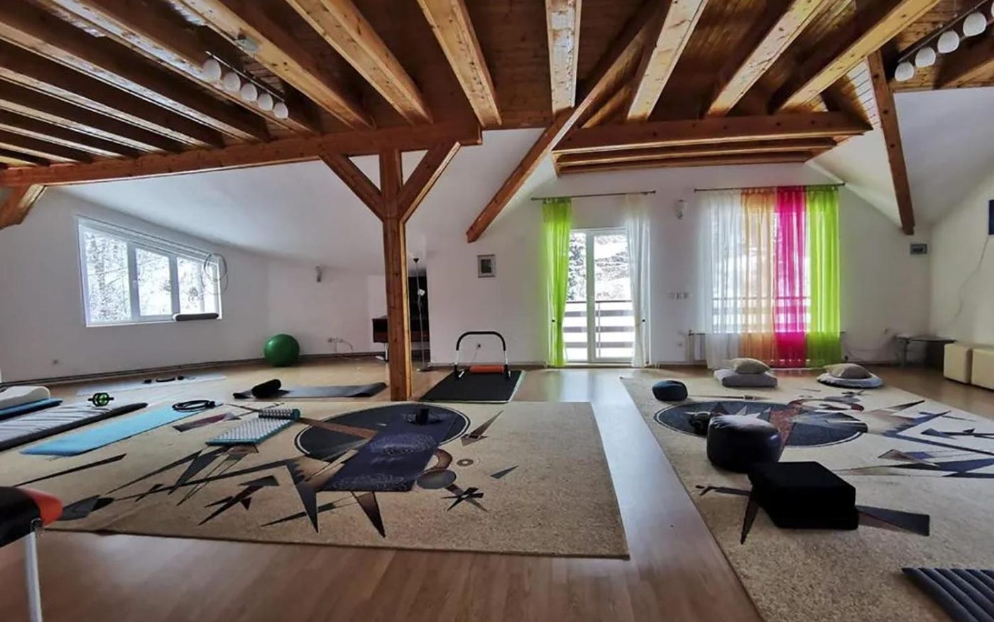 Sala de la mansardă cu grinzi de lemn și saltele de yoga